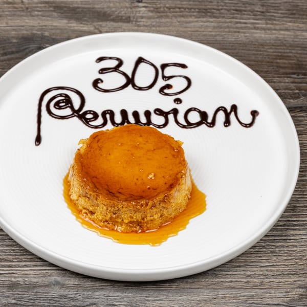 Peruvian flan dessert with caramel sauce and "305 Peruvian" written in chocolate on a white plate.