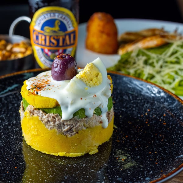 Peruvian causa with tuna, avocado, egg, and olive, served with a Cristal beer.